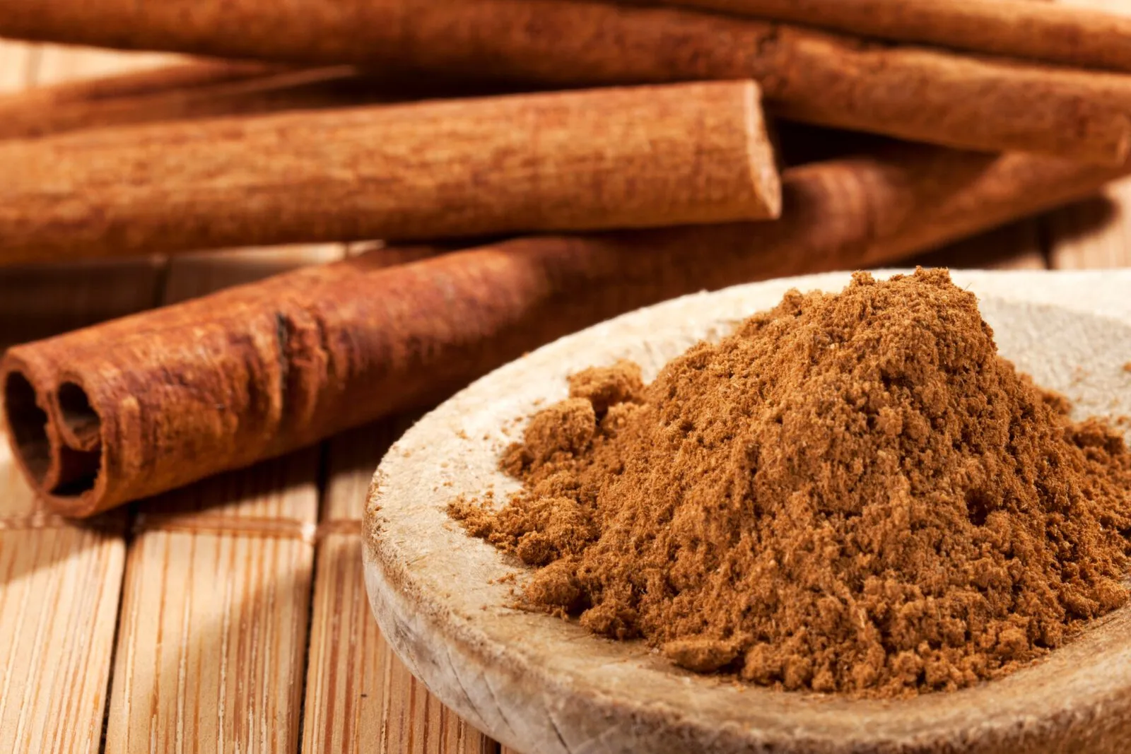 Indonesian cassia cinnamon sticks beside a bowl of ground cinnamon powder